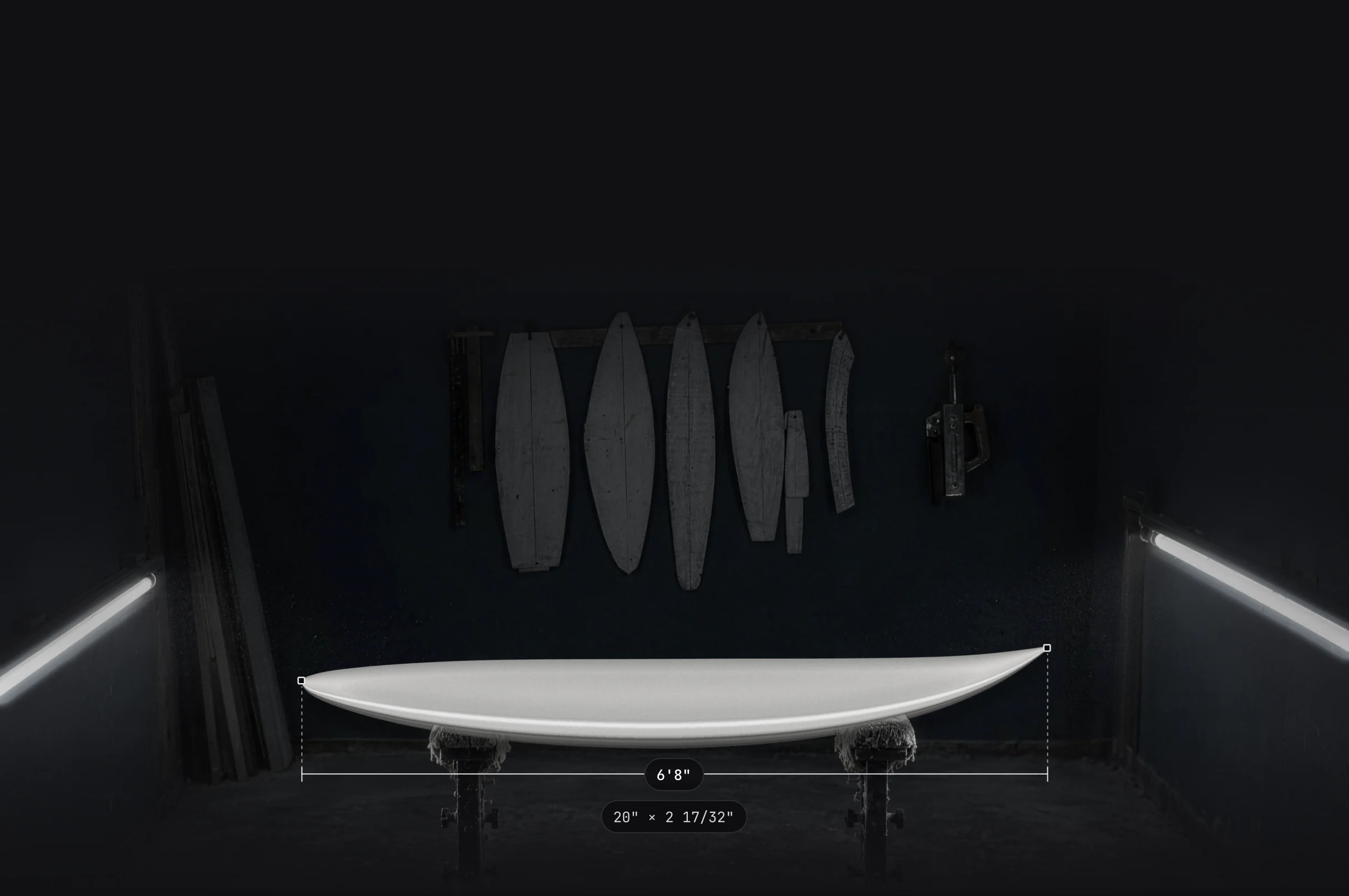 A finished 6'8" board on shaping stands in a dark shaping bay, with its length measured