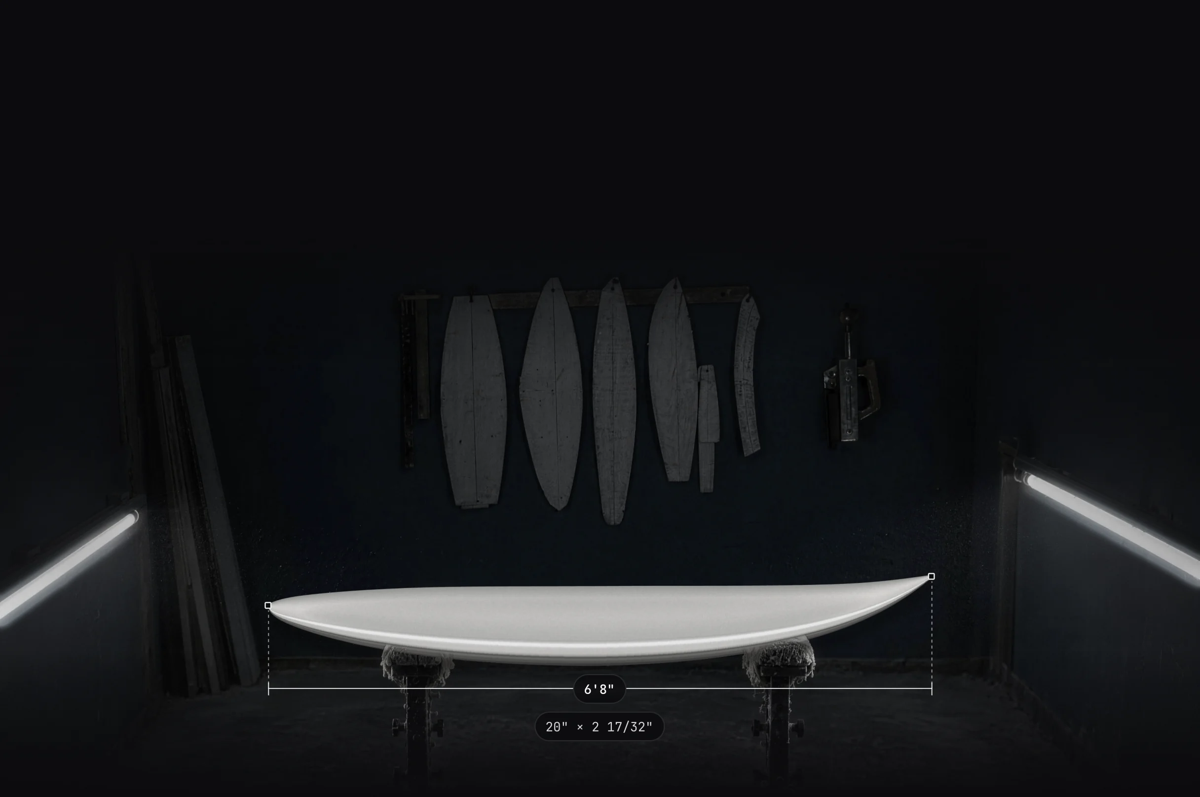 A finished 6'8" board on shaping stands in a dark shaping bay, with its length measured